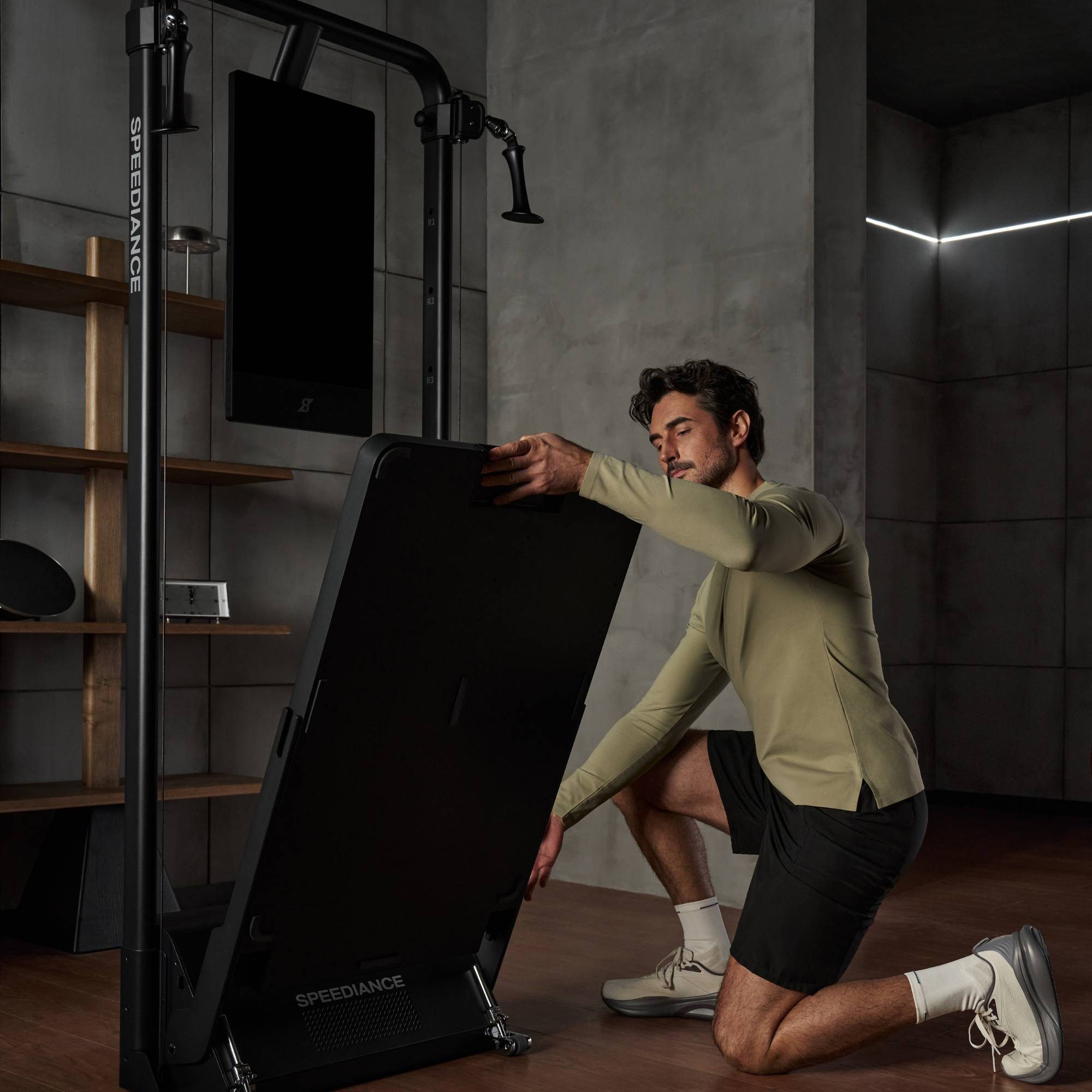 Man stelt een zwarte Speediance fitnessmachine met scherm af in een moderne sportschool.