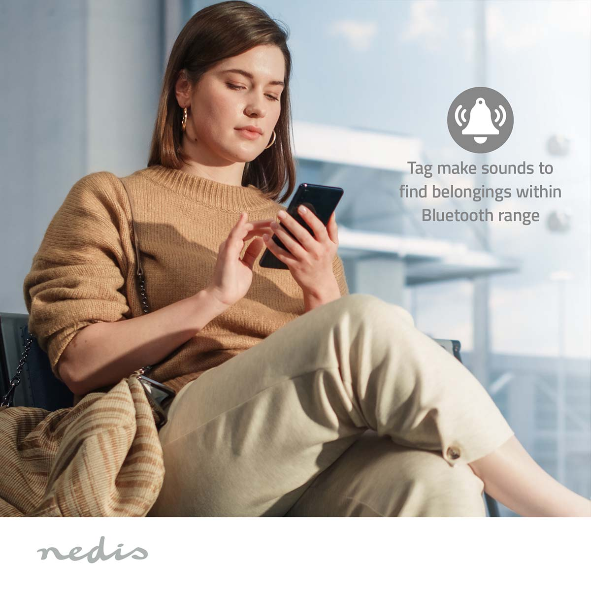 Woman in beige sweater and pants uses smartphone. Bell icon signifies tracking.