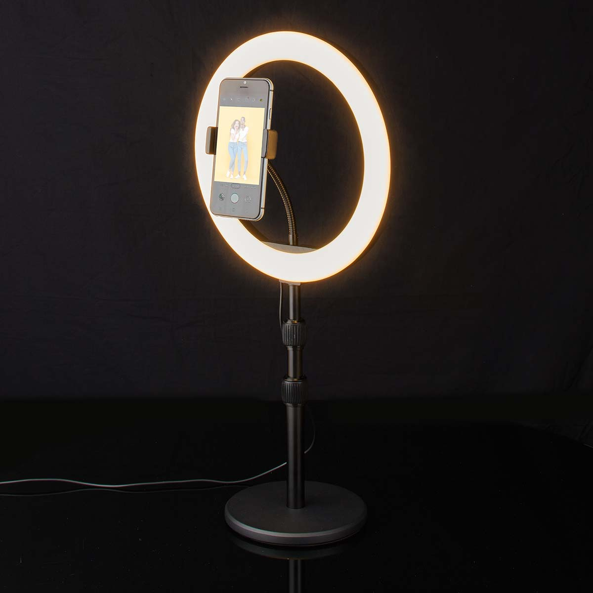 Un smartphone est tenu par une lumière annulaire sur un trépied.