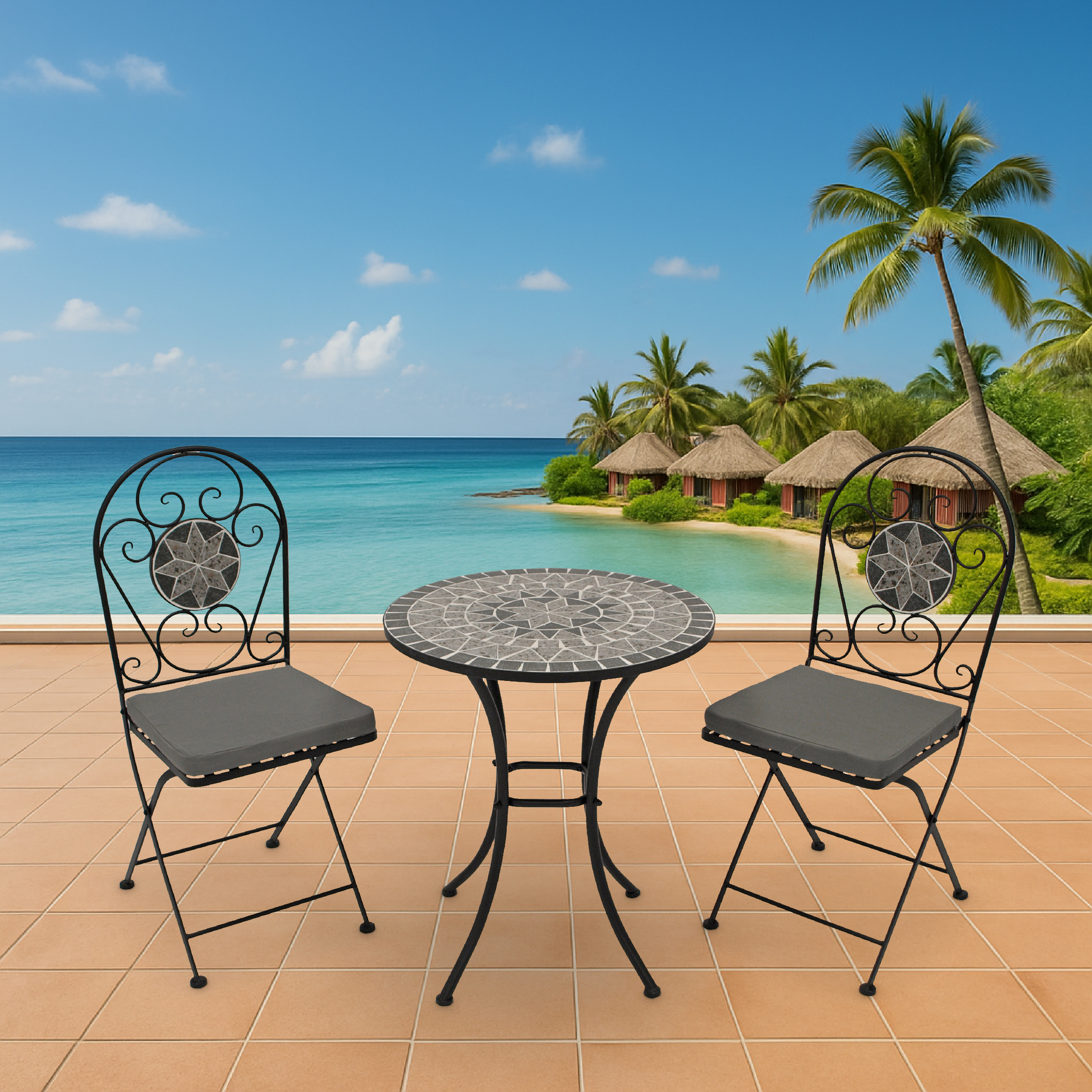 Ein Mosaiktisch und zwei Stühle stehen auf einer Terrasse mit Blick auf das Meer und Hütten.
