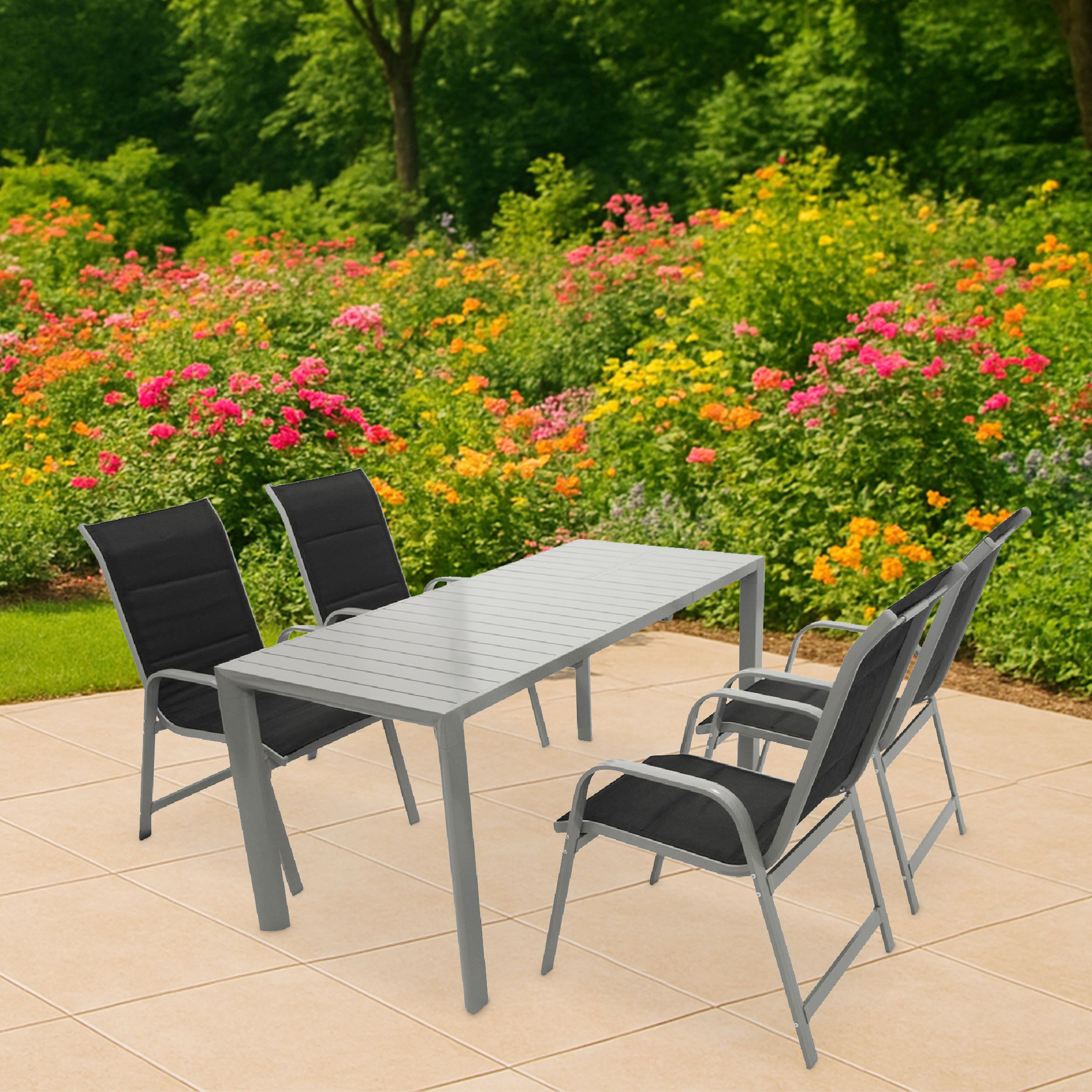 Ein grauer Tisch mit vier schwarzen Stühlen auf einer beigen Terrasse, blühende Blumen im Hintergrund.