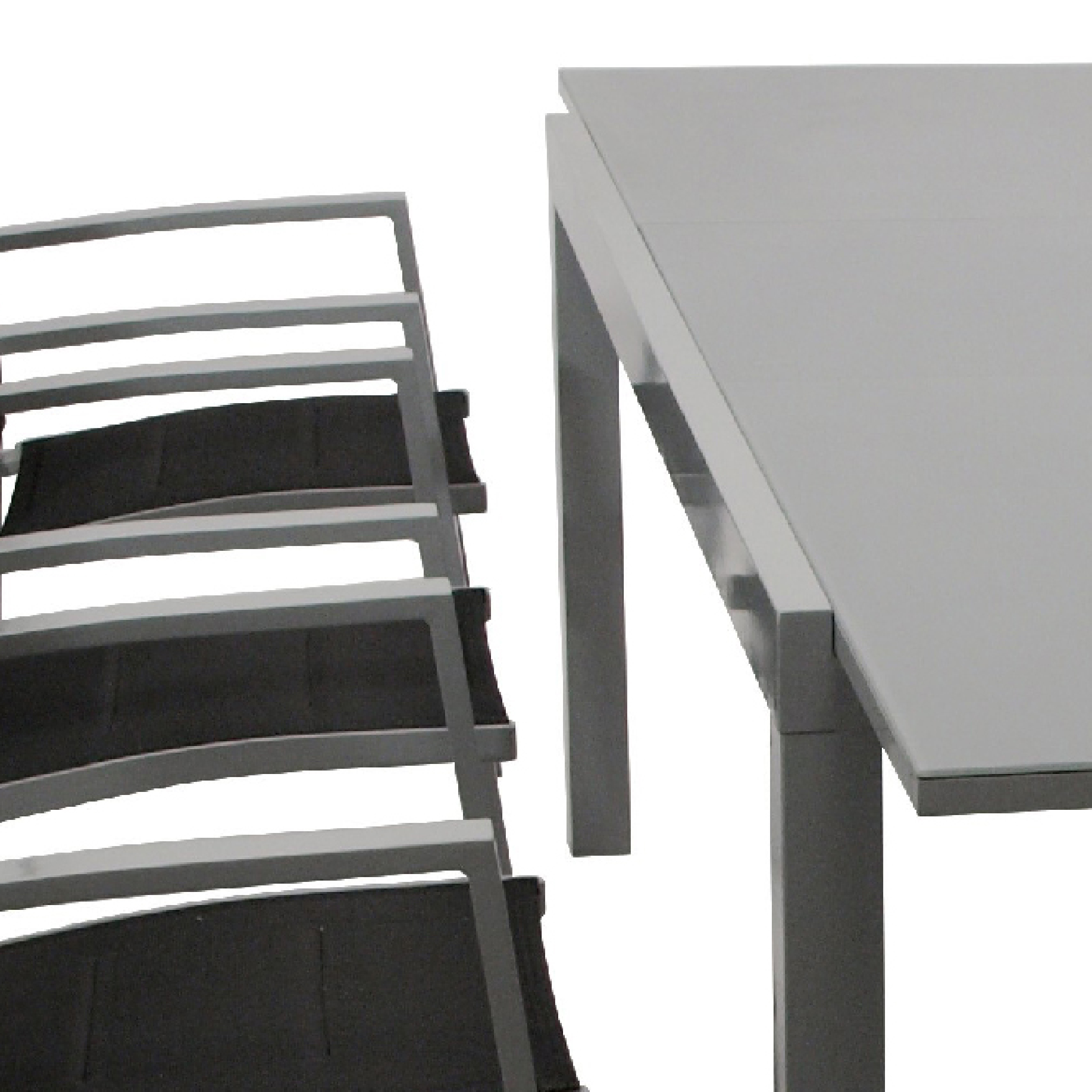 Ein grauer Tisch und vier schwarze Stühle mit Metallrahmen.