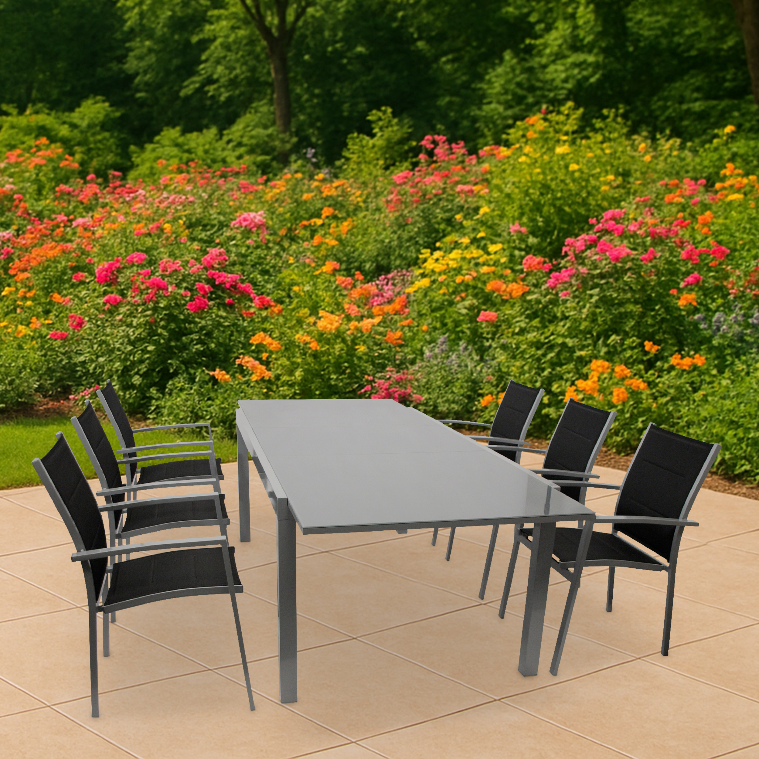 Ein grauer Tisch mit schwarzen Stühlen auf einer hellbeigen gefliesten Terrasse.