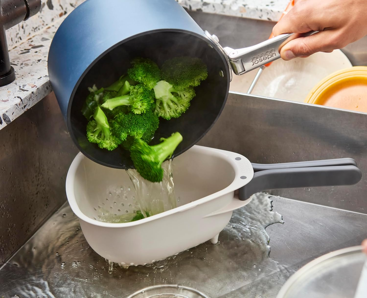 Grüner Brokkoli wird aus einem Topf in ein Sieb geschüttet, Wasser fließt ab.