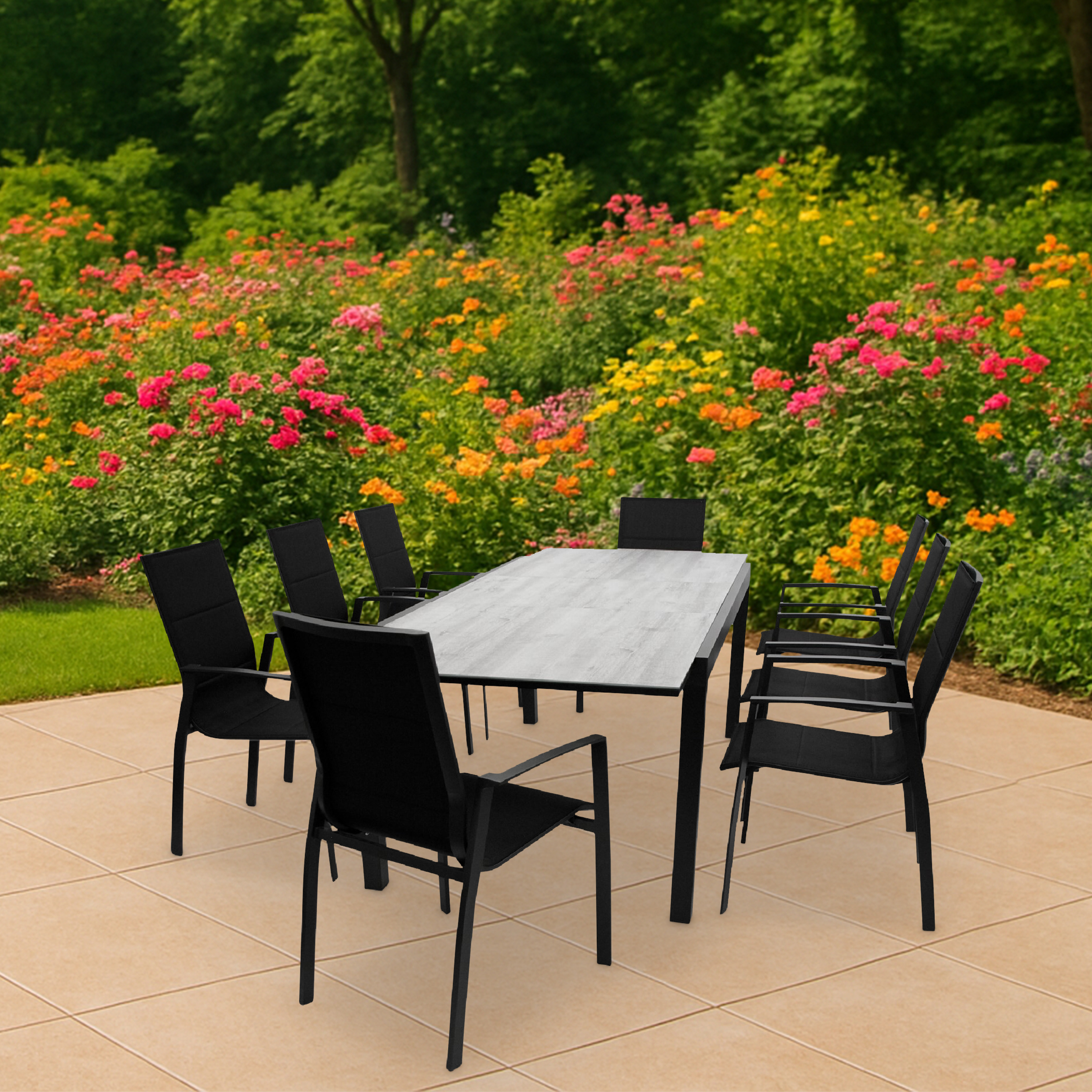 Schwarze Gartenmöbel mit Tisch und Stühlen auf einer Terrasse, im Hintergrund bunte Blumen.