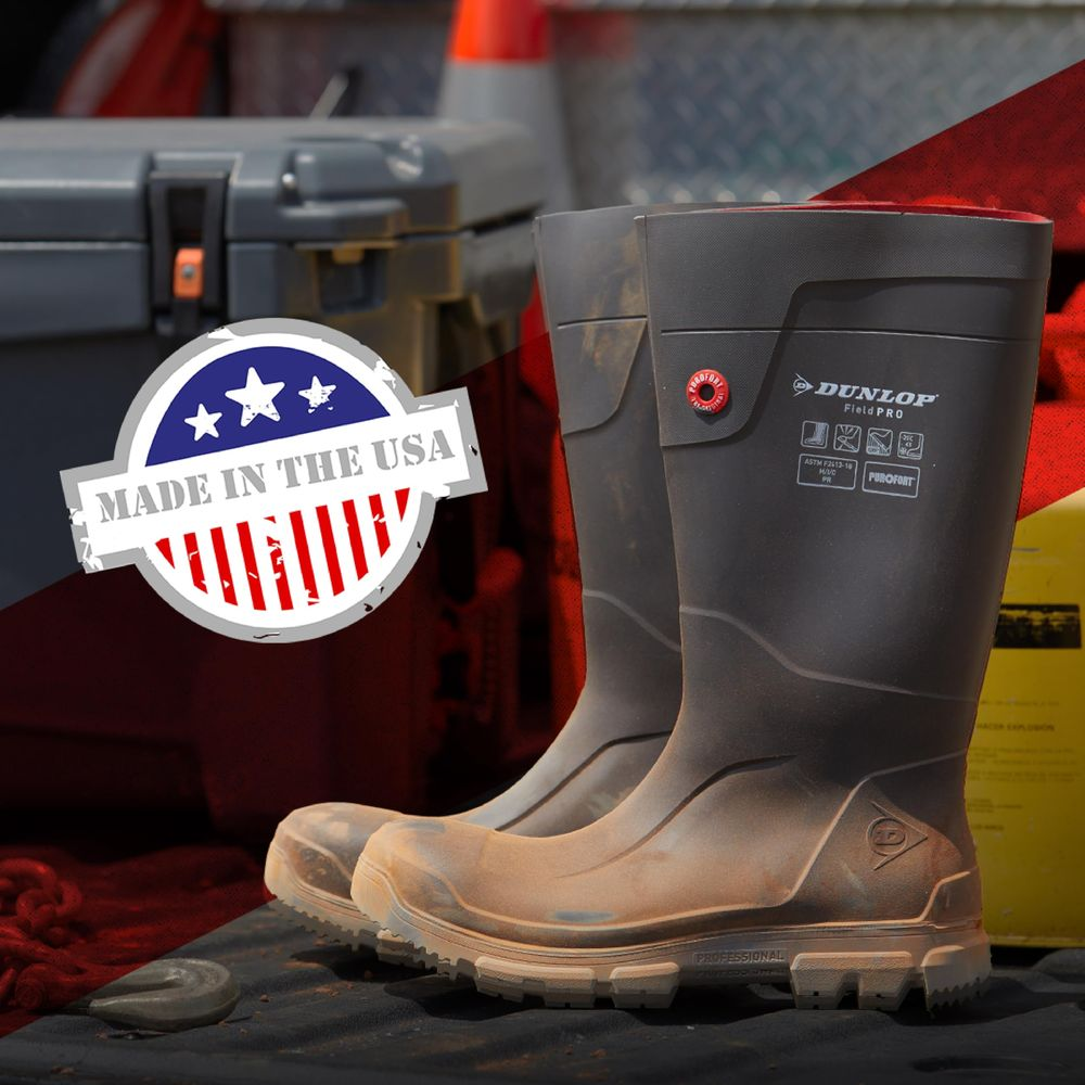 Schwarze Dunlop Gummistiefel mit "Made in USA"-Aufkleber und Werkzeugkasten im Hintergrund.