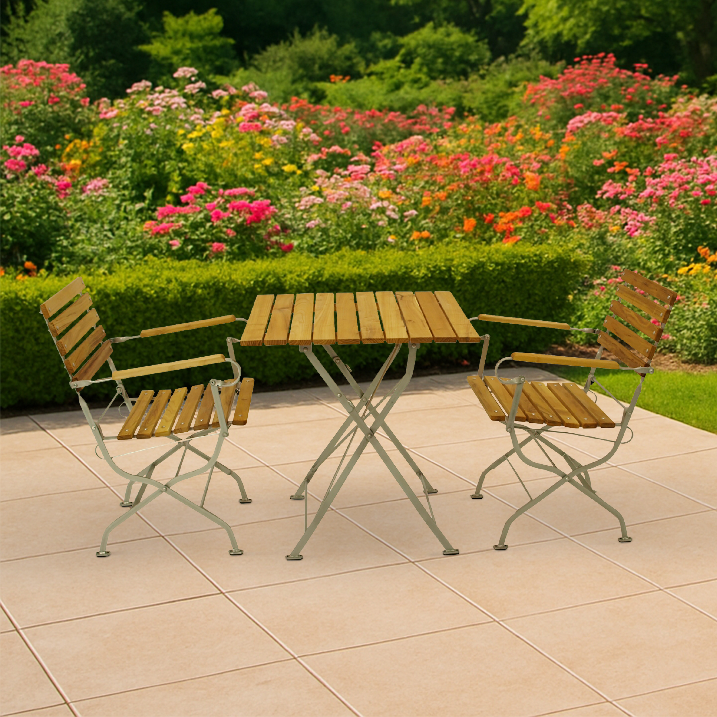 Ein Holztisch und zwei Stühle stehen auf einer Terrasse vor einem blühenden Rosengarten.