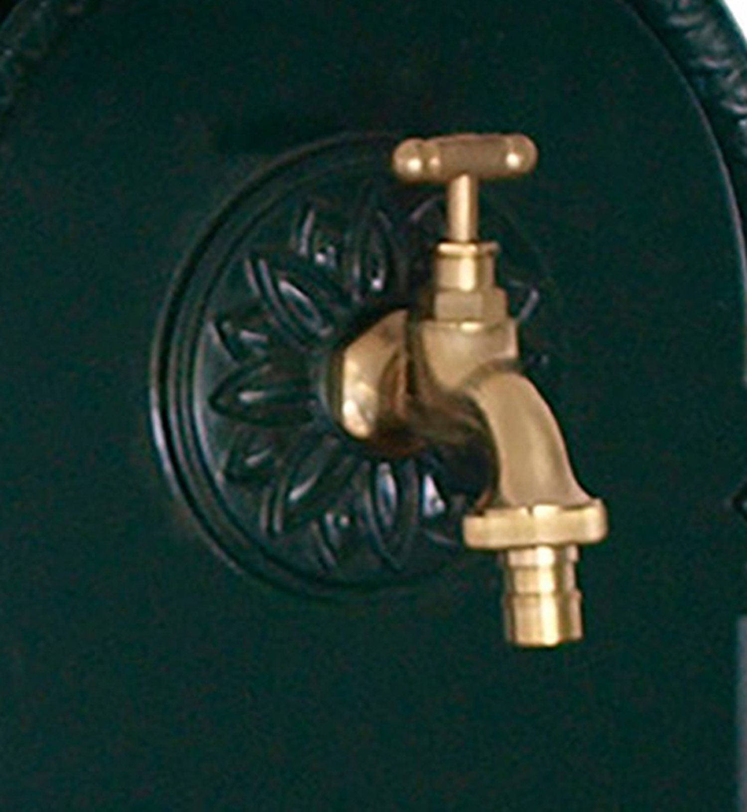 Ein goldener Wasserhahn mit T-Griff auf einem dunklen, verzierten Hintergrund.