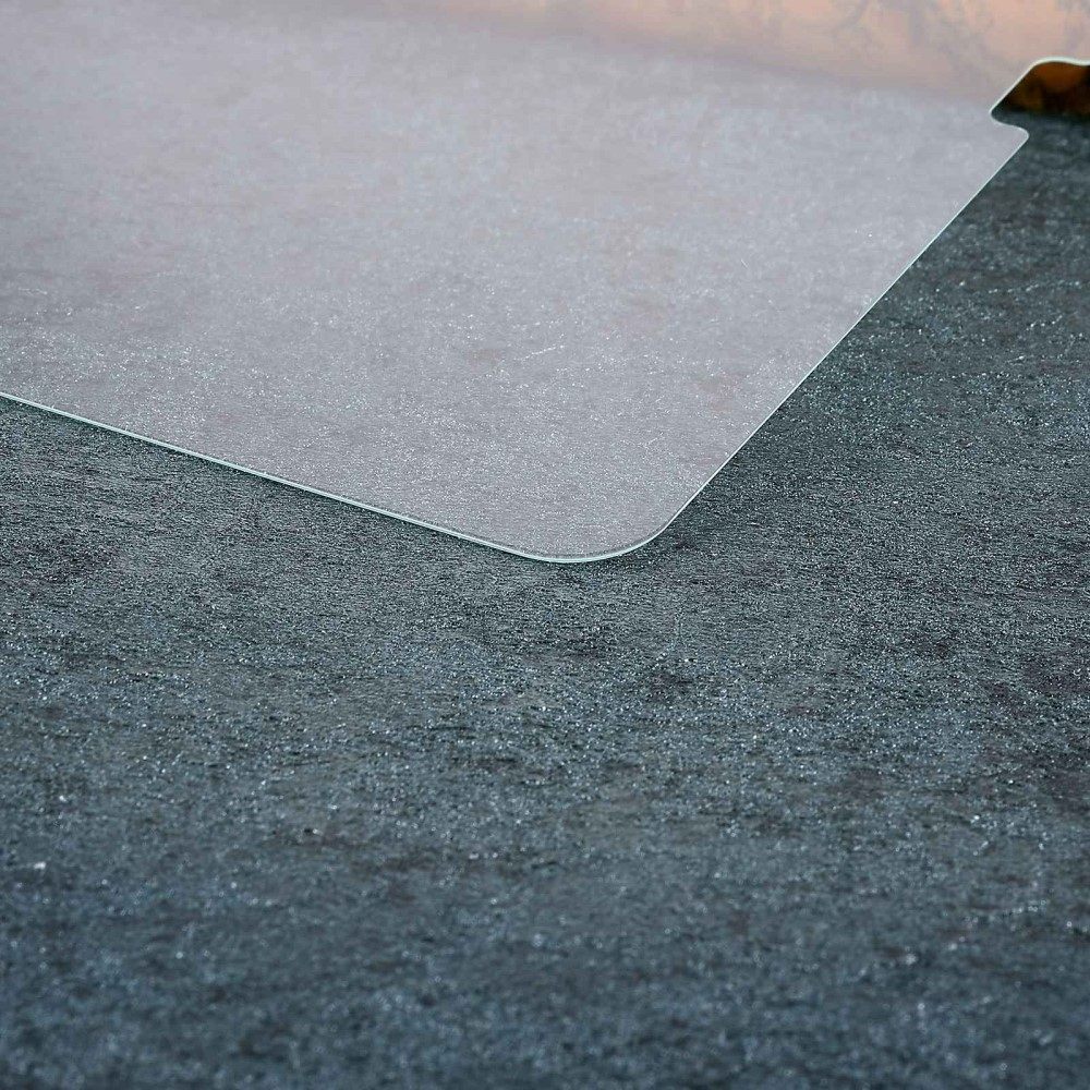 Un tapis transparent repose sur une surface sombre et texturée.