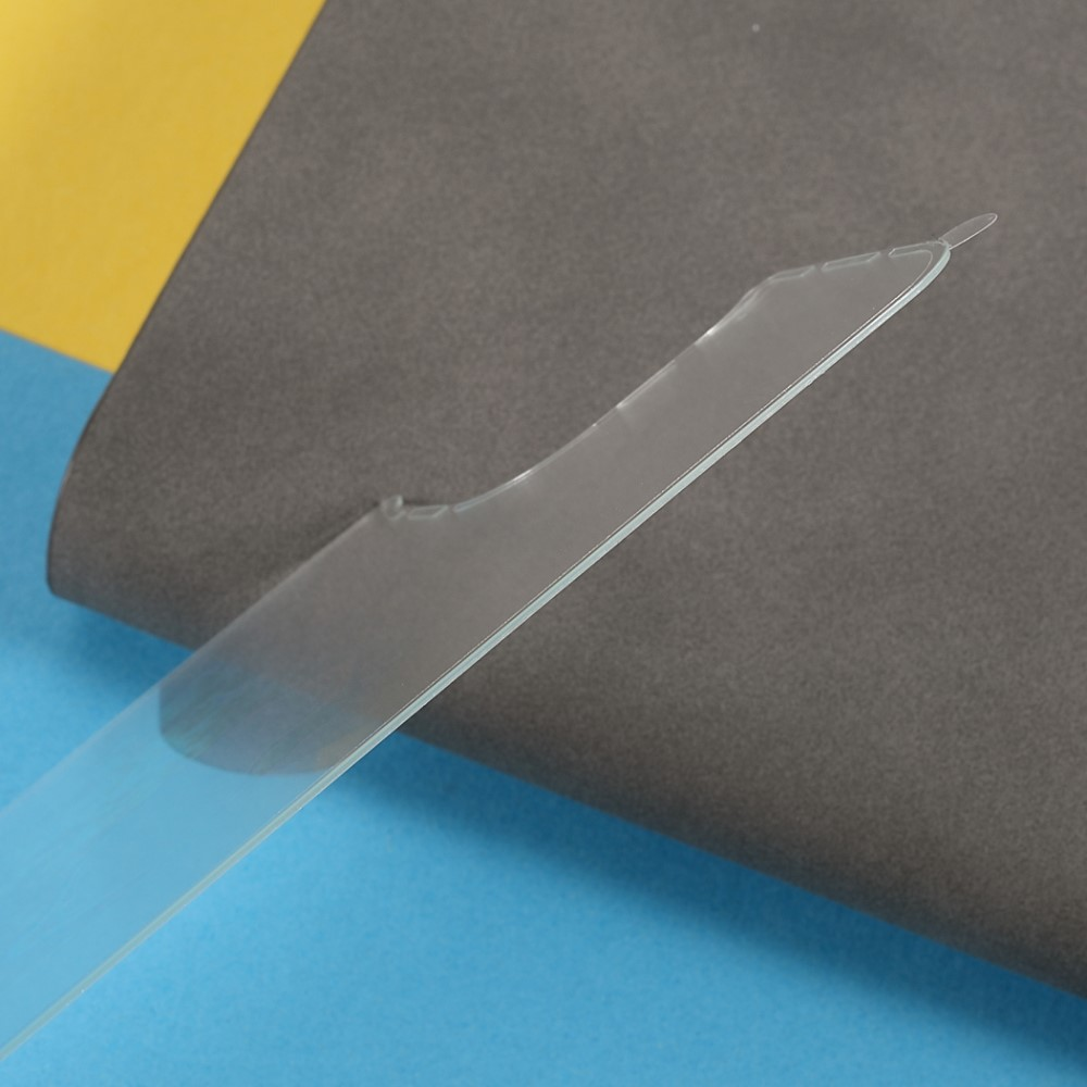 Un pezzo di plastica trasparente con punta poggia su materiale grigio e blu.