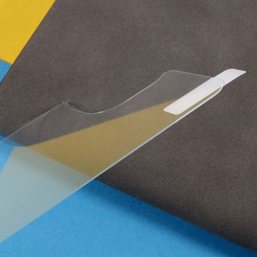 Un film protecteur transparent avec languette blanche se décolle d'une surface.