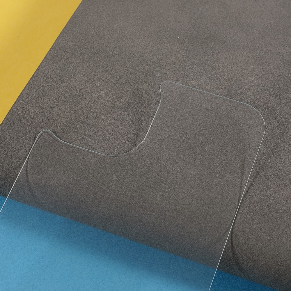 Un film protecteur transparent sur tissu foncé, avec du tissu jaune et bleu à côté.