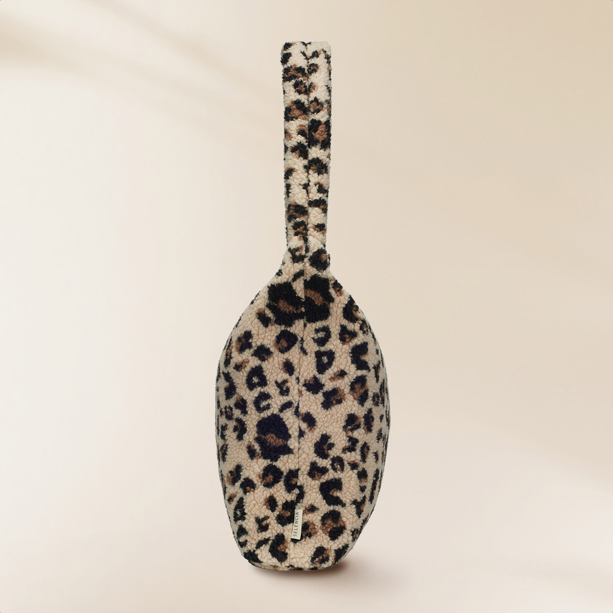 A fluffy leopard print bag with a handle, against a light background.