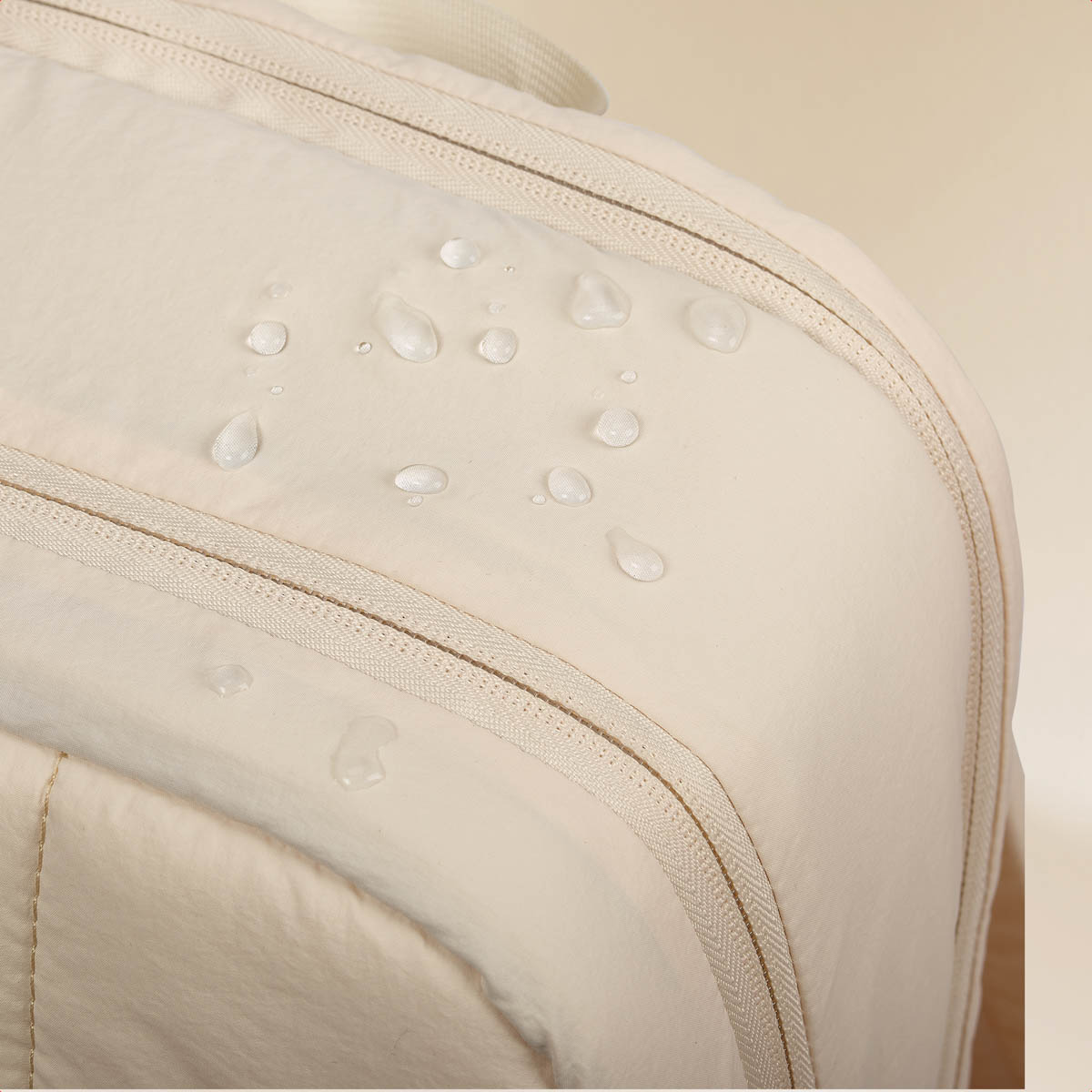 Water droplets on cream fabric with zipper detail.