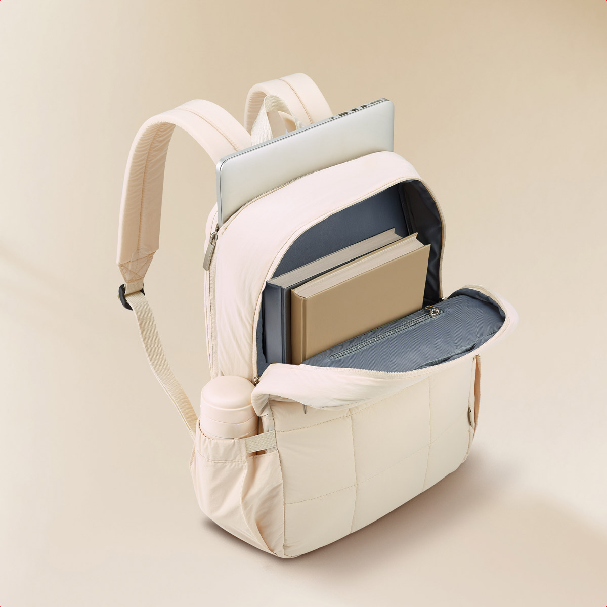 A light beige backpack with books and a laptop, a water bottle on the side.