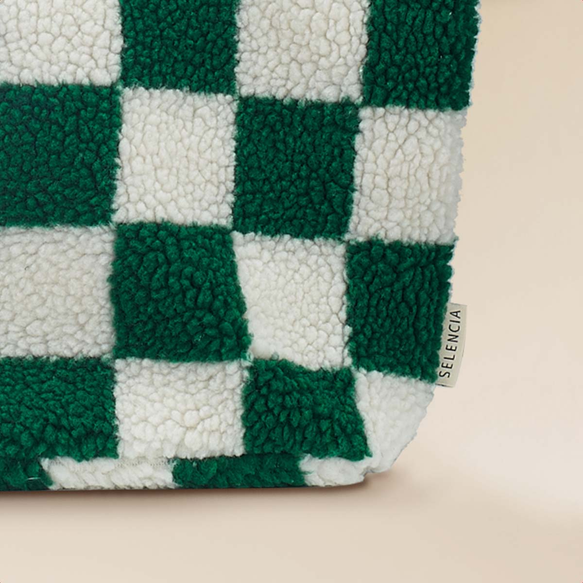 A teddy bear fabric with a green and white checkerboard pattern, close-up.