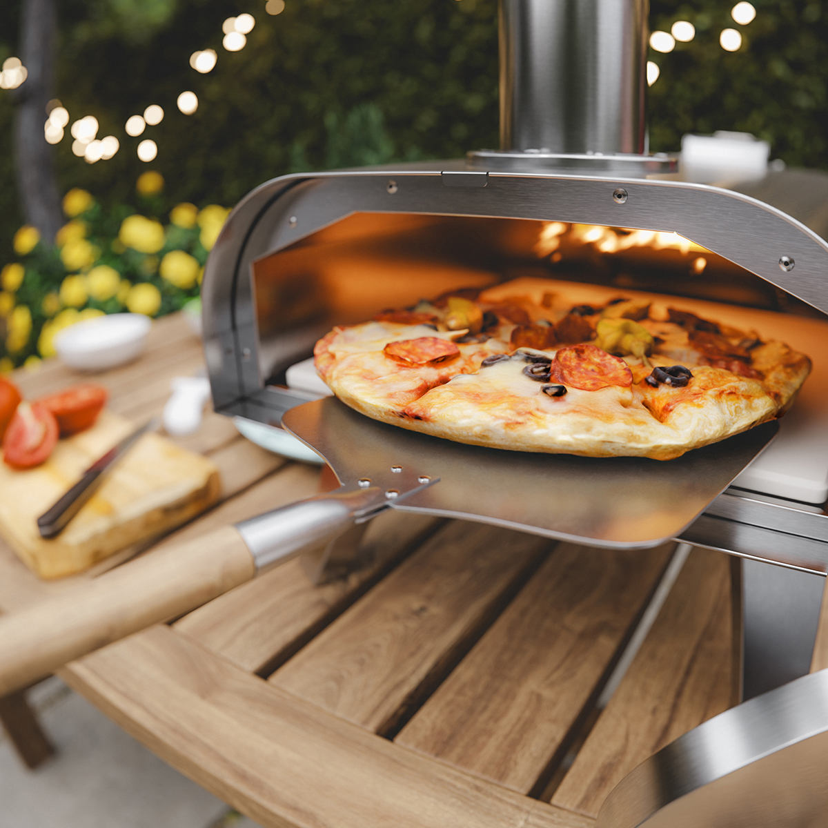 Pizza uit oven gehaald met pizzaplank. Buiten 's nachts met lampjes.