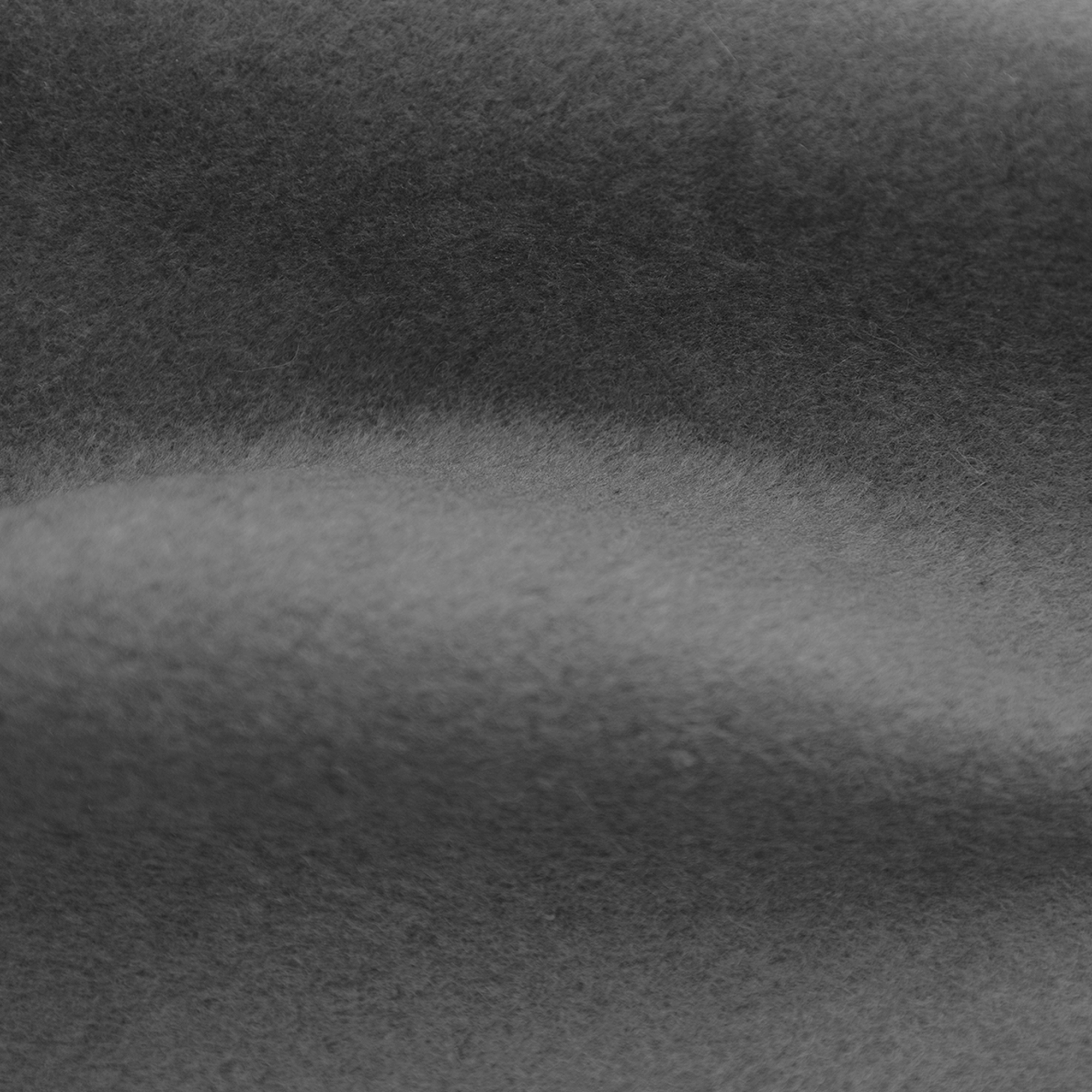 Gros plan d'un tissu gris foncé et flou avec un éclairage doux et une texture subtile.