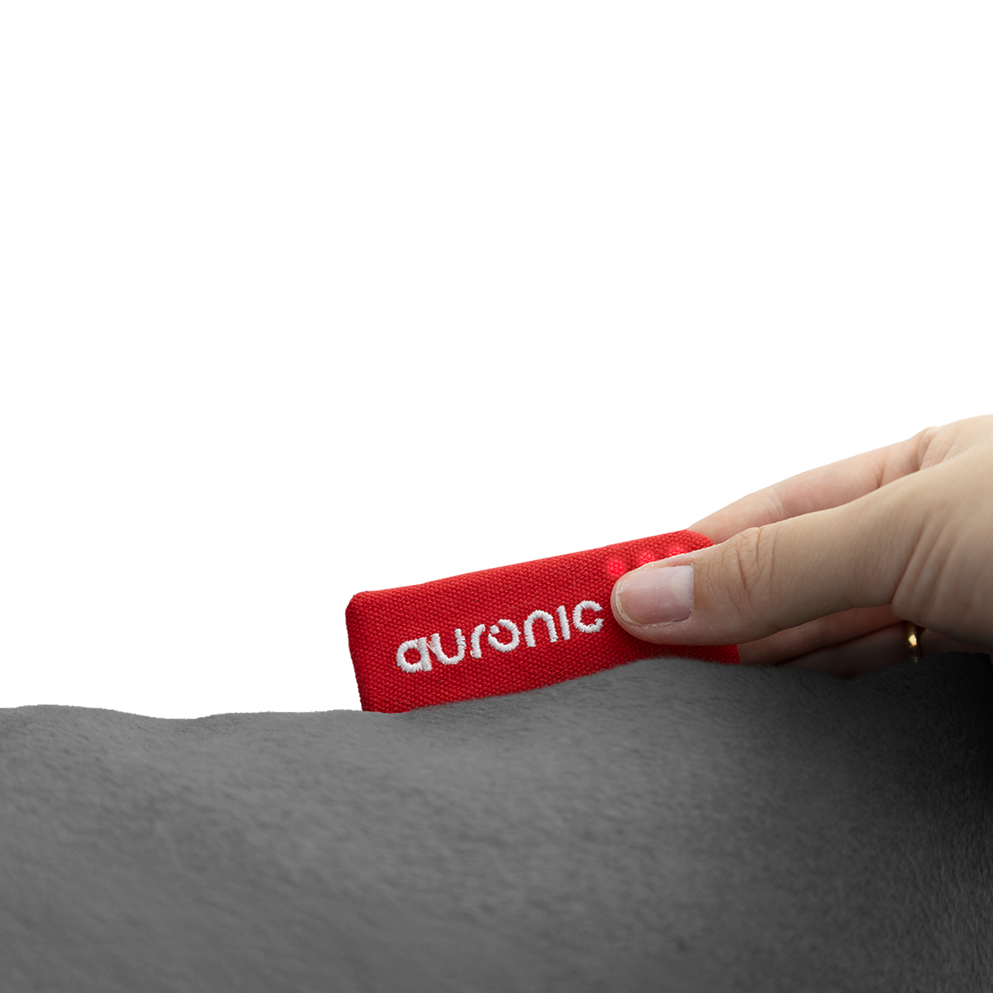 Une main tient une étiquette rouge avec texte blanc sur tissu gris.