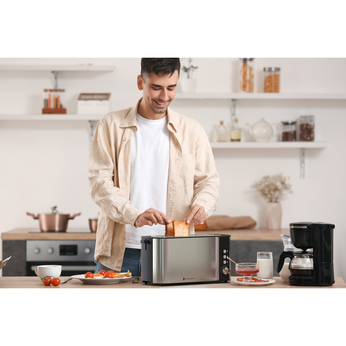 A man prepares toast in a toaster in a kitchen. Jam and coffee are on the table.