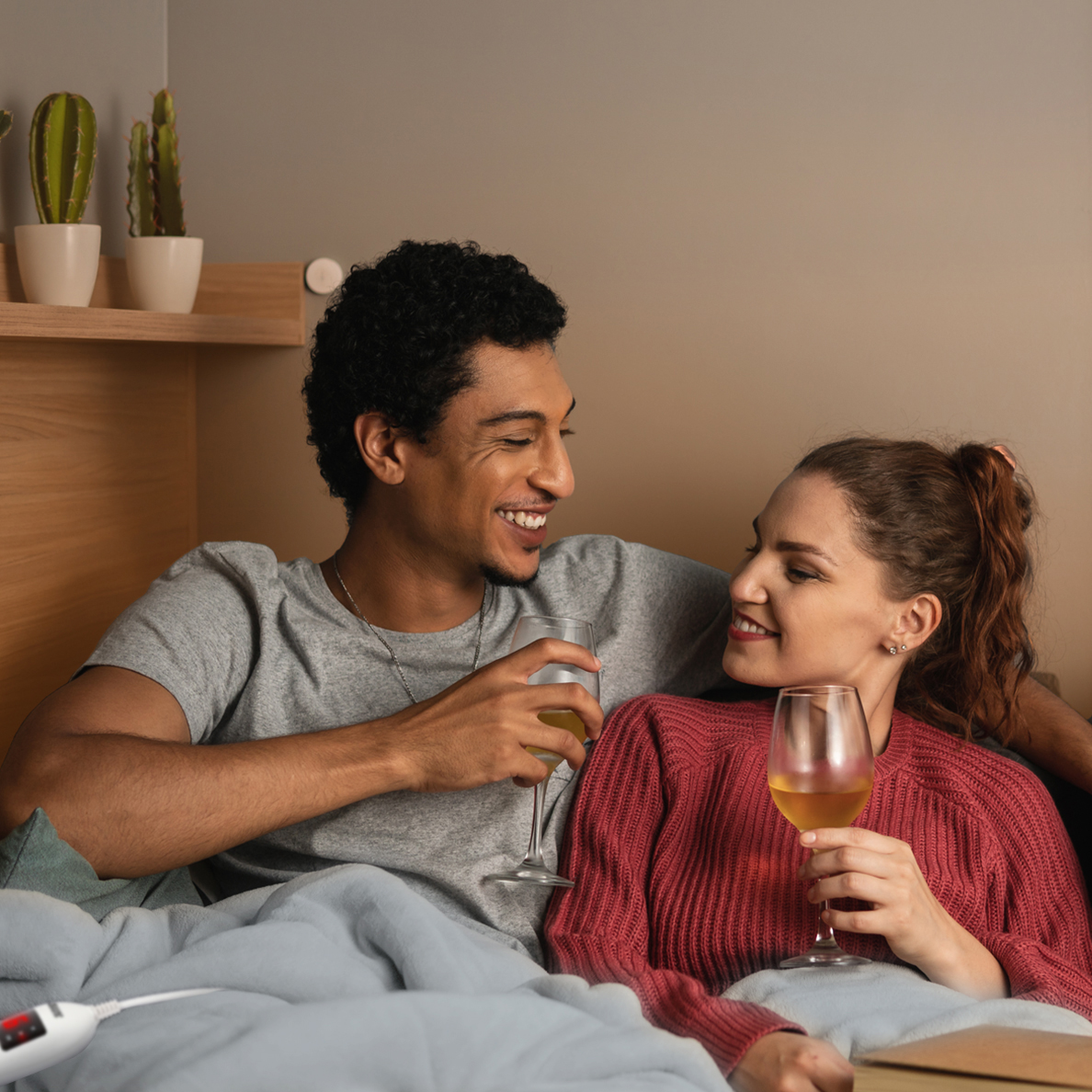 A man and a woman drink wine and smile at each other.