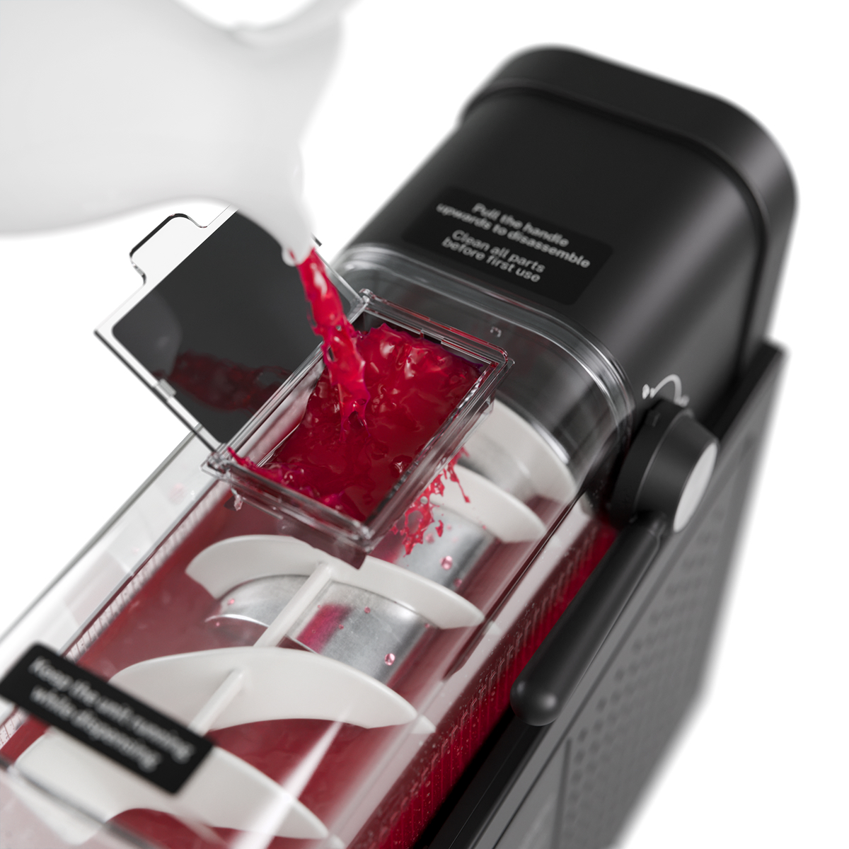 Red juice is poured into a juicer. White spirals are visible.