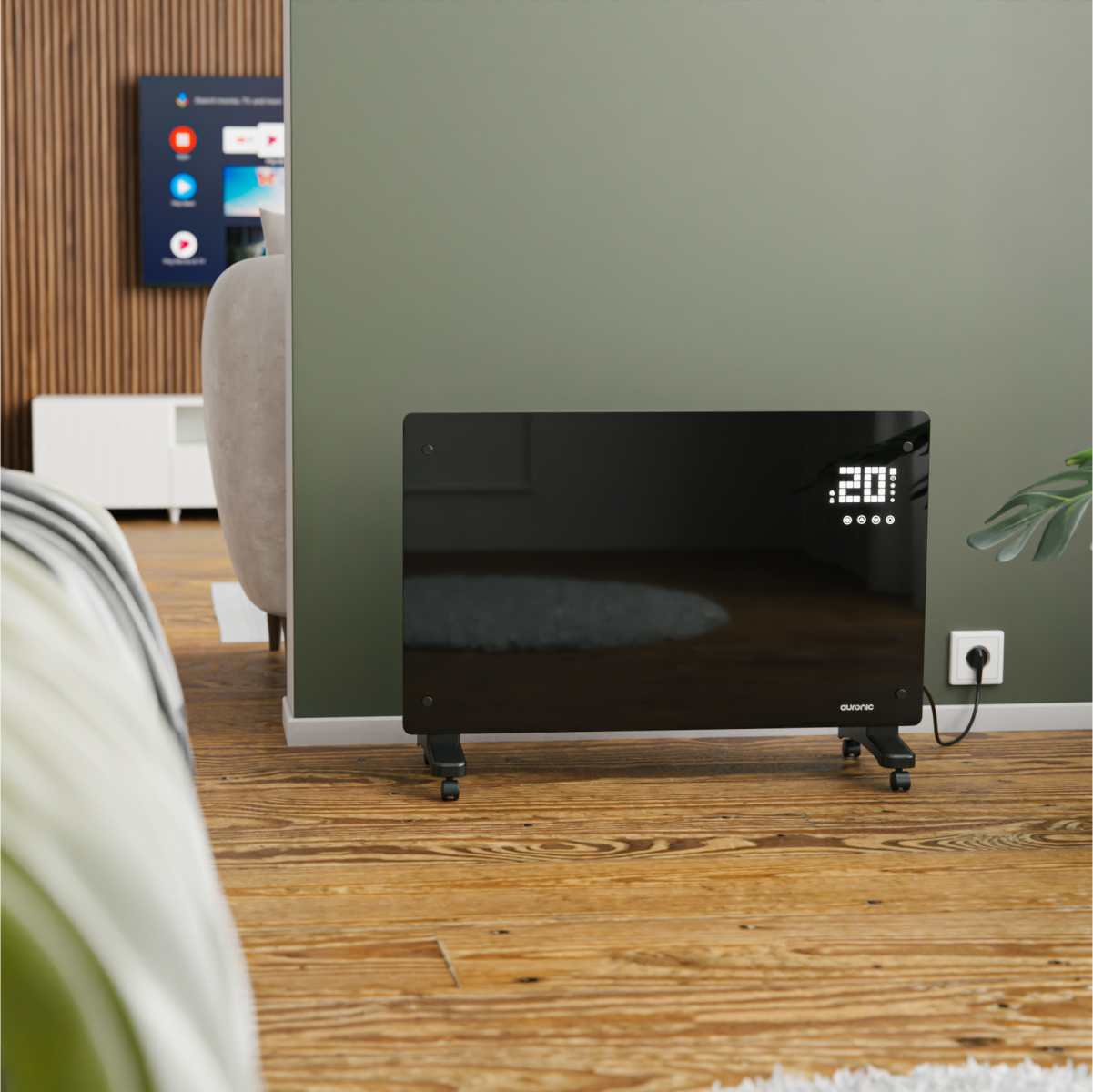 Een zwarte elektrische kachel met wielen staat op een houten vloer tegen een groene muur.