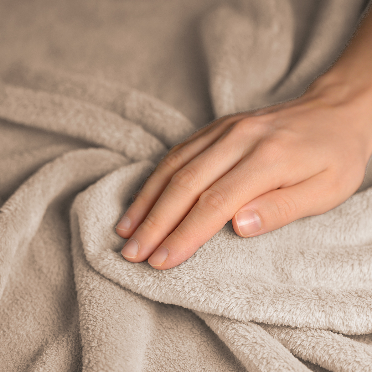 A human hand rests on a soft, beige fabric.
