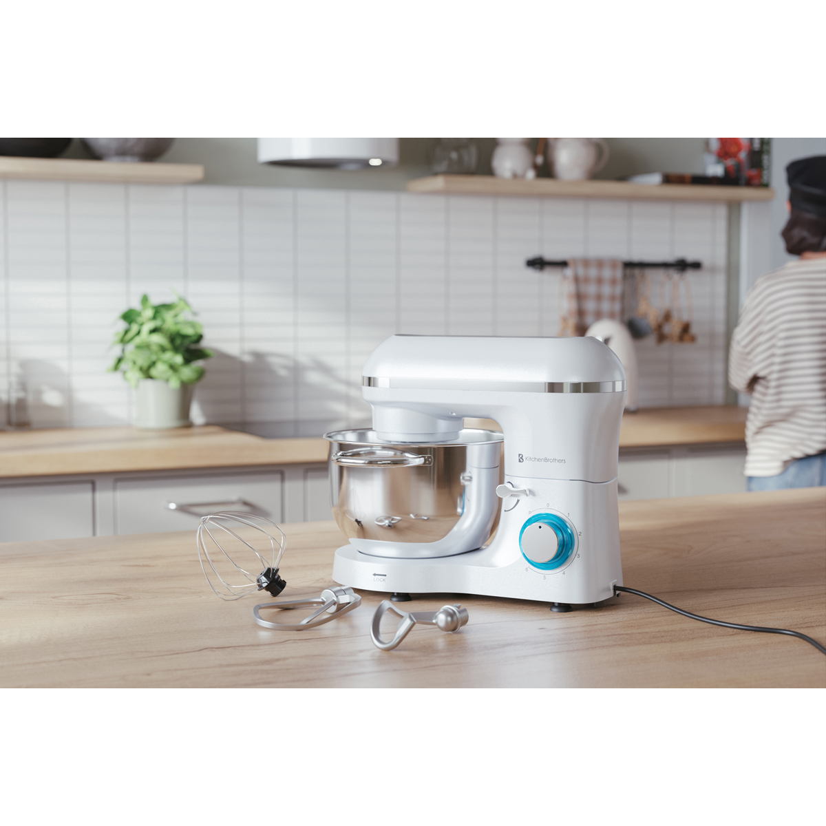 Un robot pâtissier blanc avec bol et accessoires sur une table en bois.