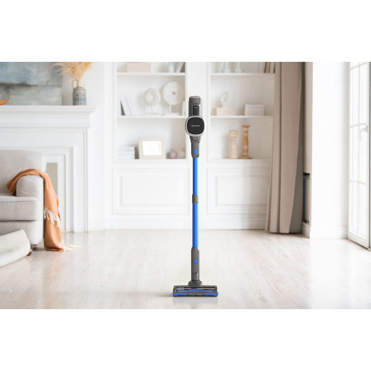 Un aspirateur sans fil bleu se tient sur un parquet dans un salon.