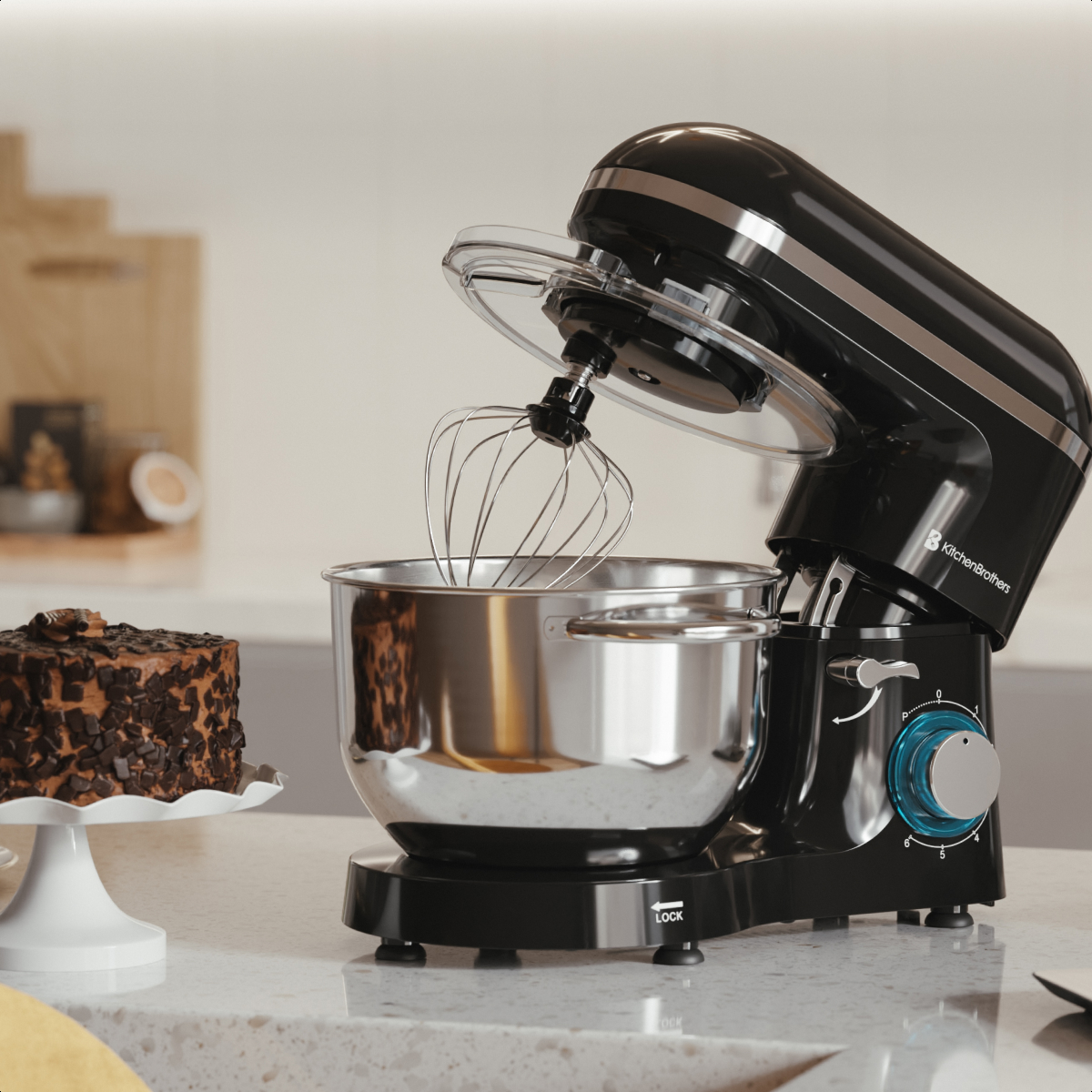 Robot pâtissier noir avec bol en inox et fouet, à côté d'un gâteau au chocolat.