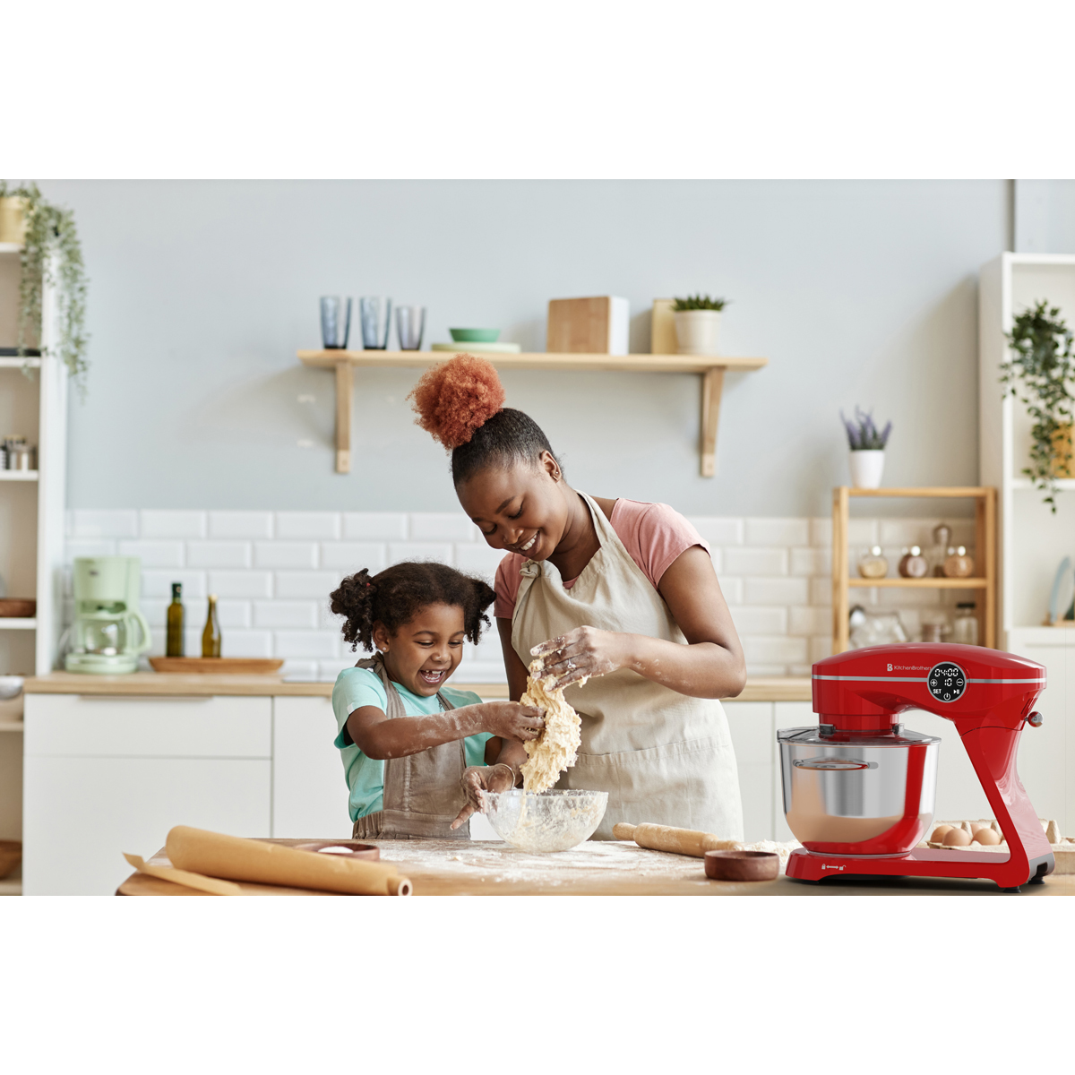 Mère et enfant pétrissent de la pâte dans une cuisine avec un robot pâtissier rouge.