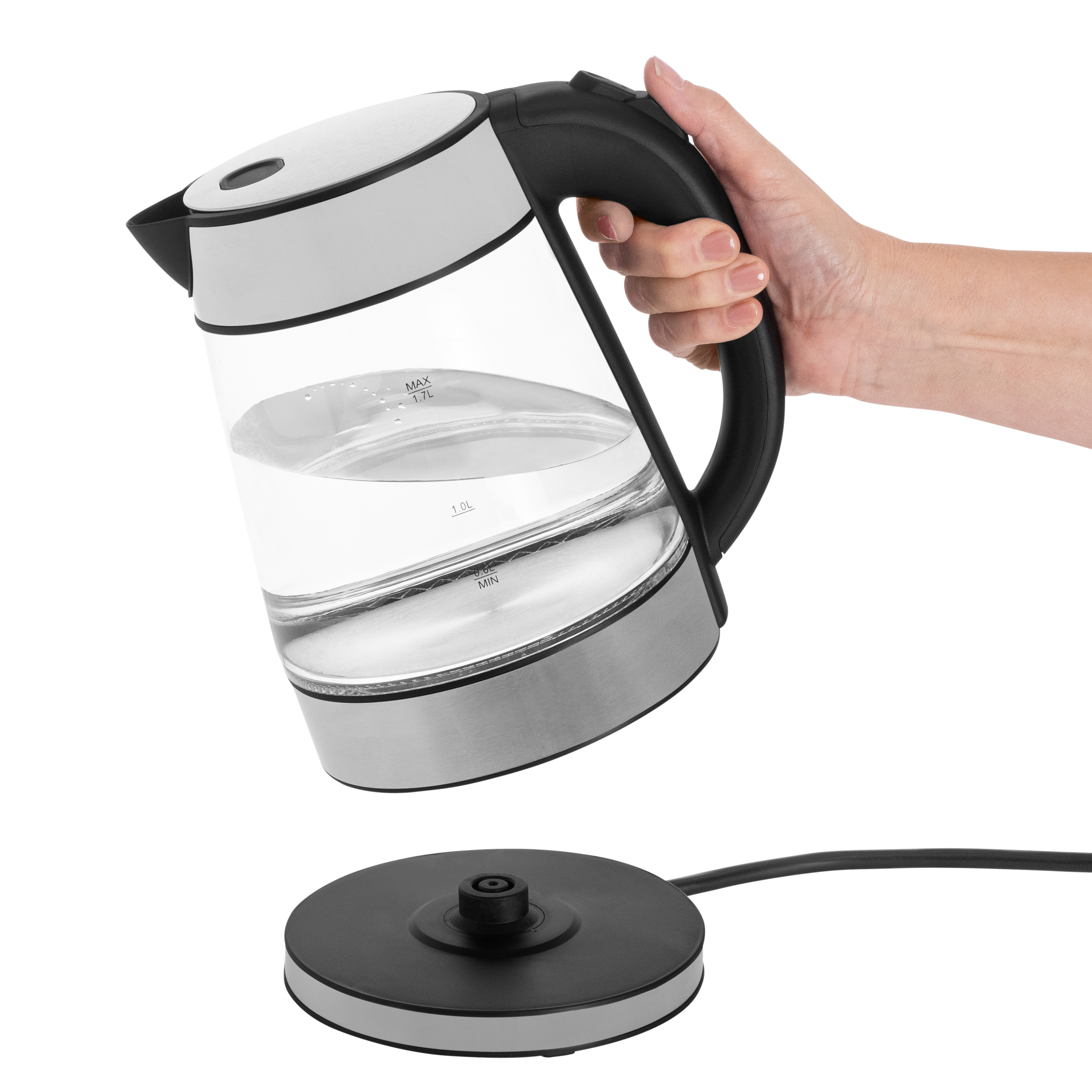 Een hand houdt een doorzichtige waterkoker gevuld met water boven een zwarte voet.