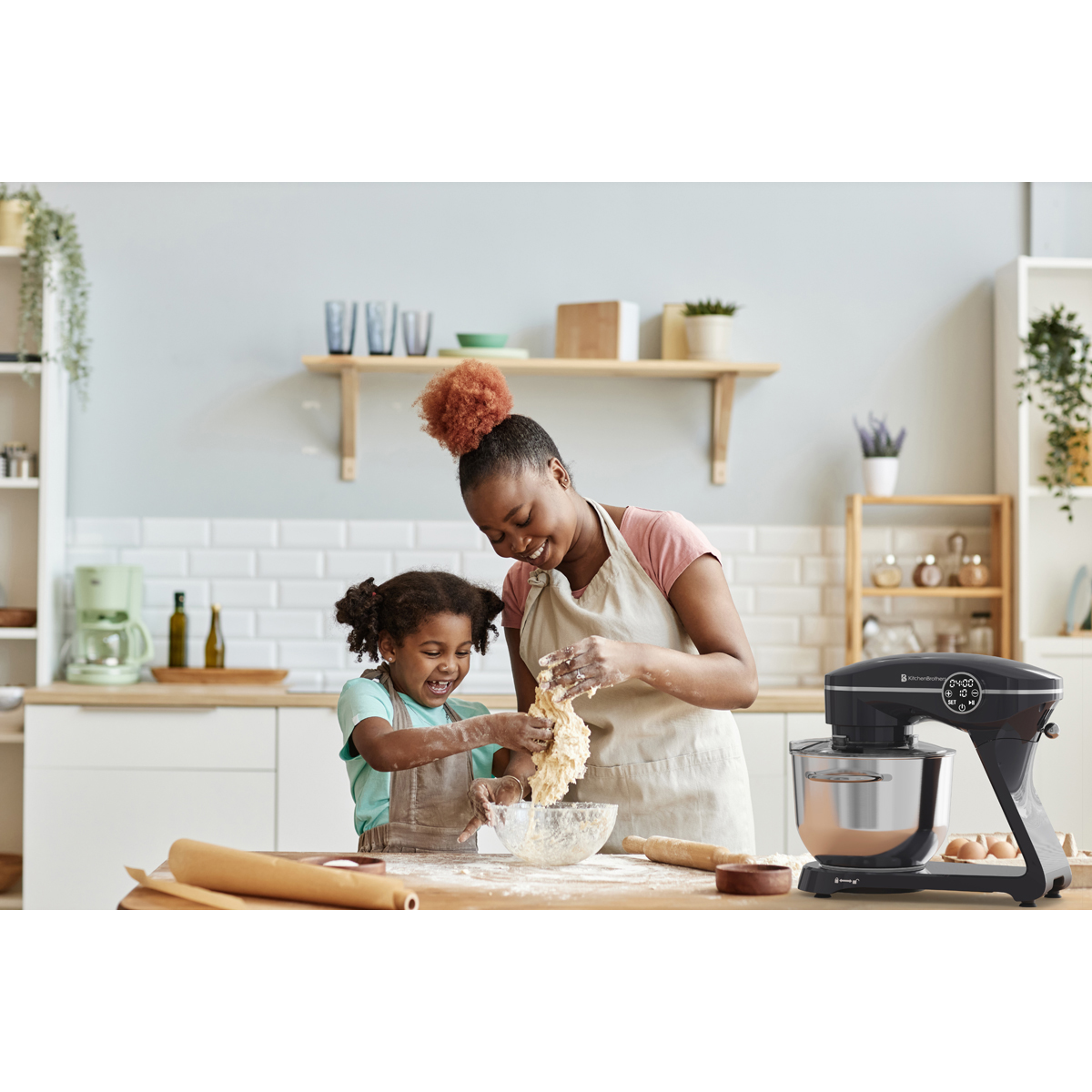 Mère et enfant pétrissent de la pâte dans une cuisine avec un robot pâtissier.