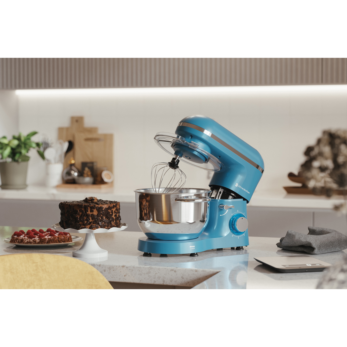 Een blauwe keukenmixer met garde staat op een aanrecht, naast taarten.