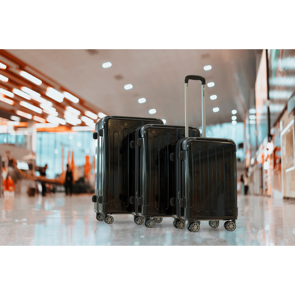 Trois valises noires se tiennent côte à côte sur un sol brillant dans un hall d'aéroport.
