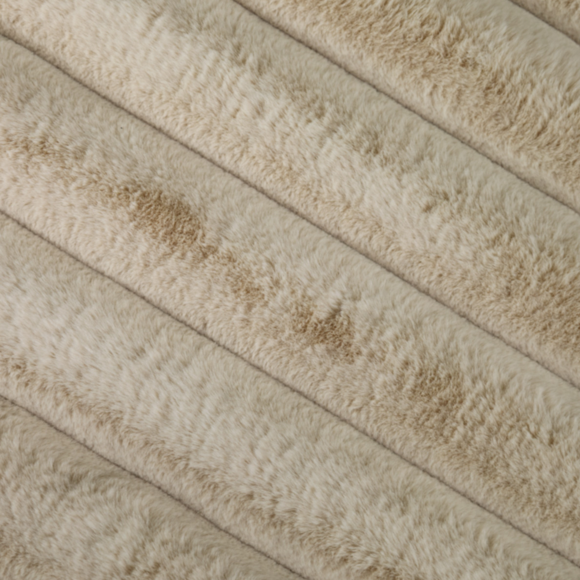 Beige plush fabric with diagonal ridges and subtle brown speckles.