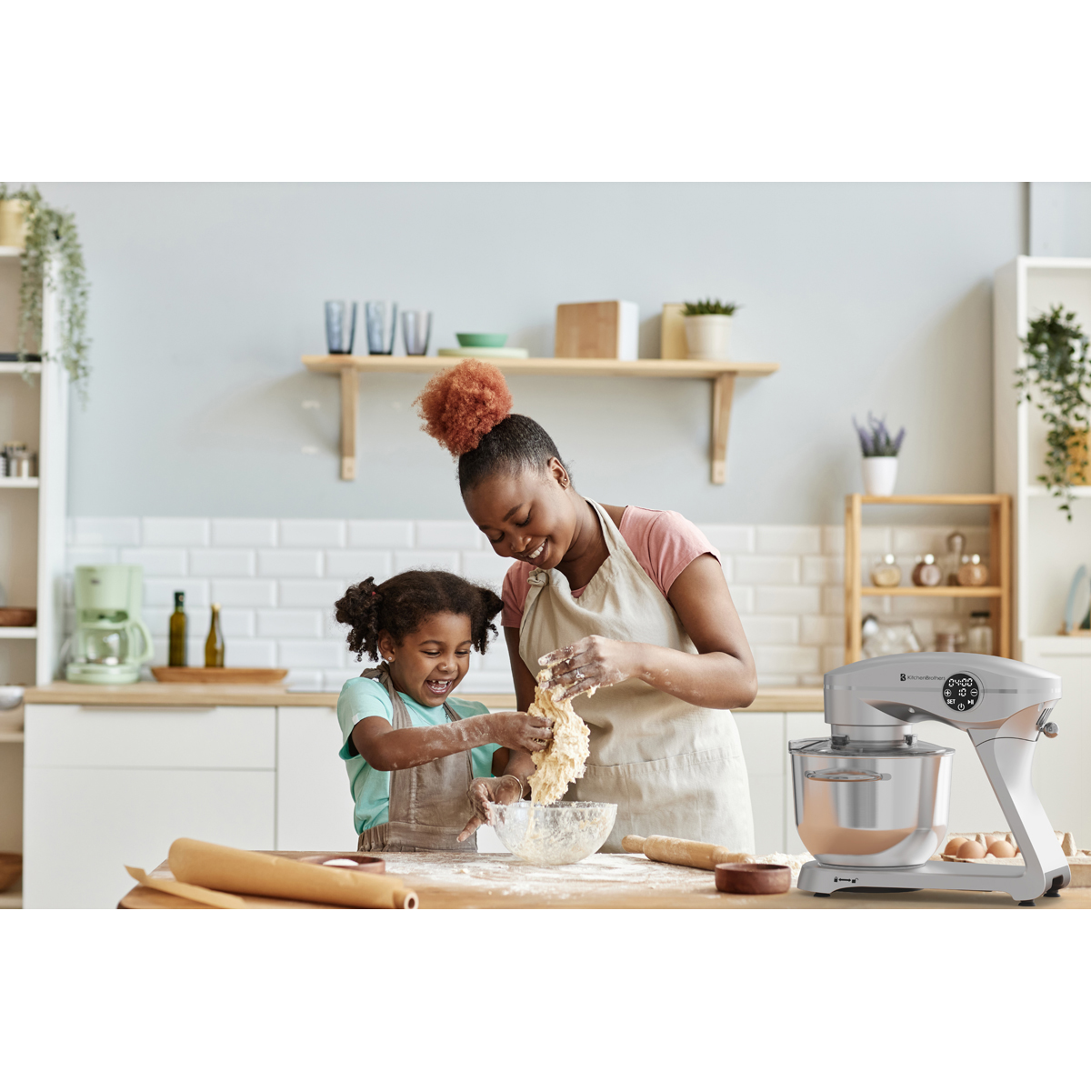 Moeder en kind kneden deeg in een keuken, met een standmixer ernaast.