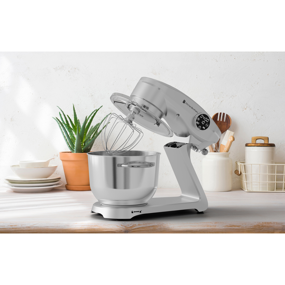 Een zilveren standmixer met garde staat op een houten ondergrond.
