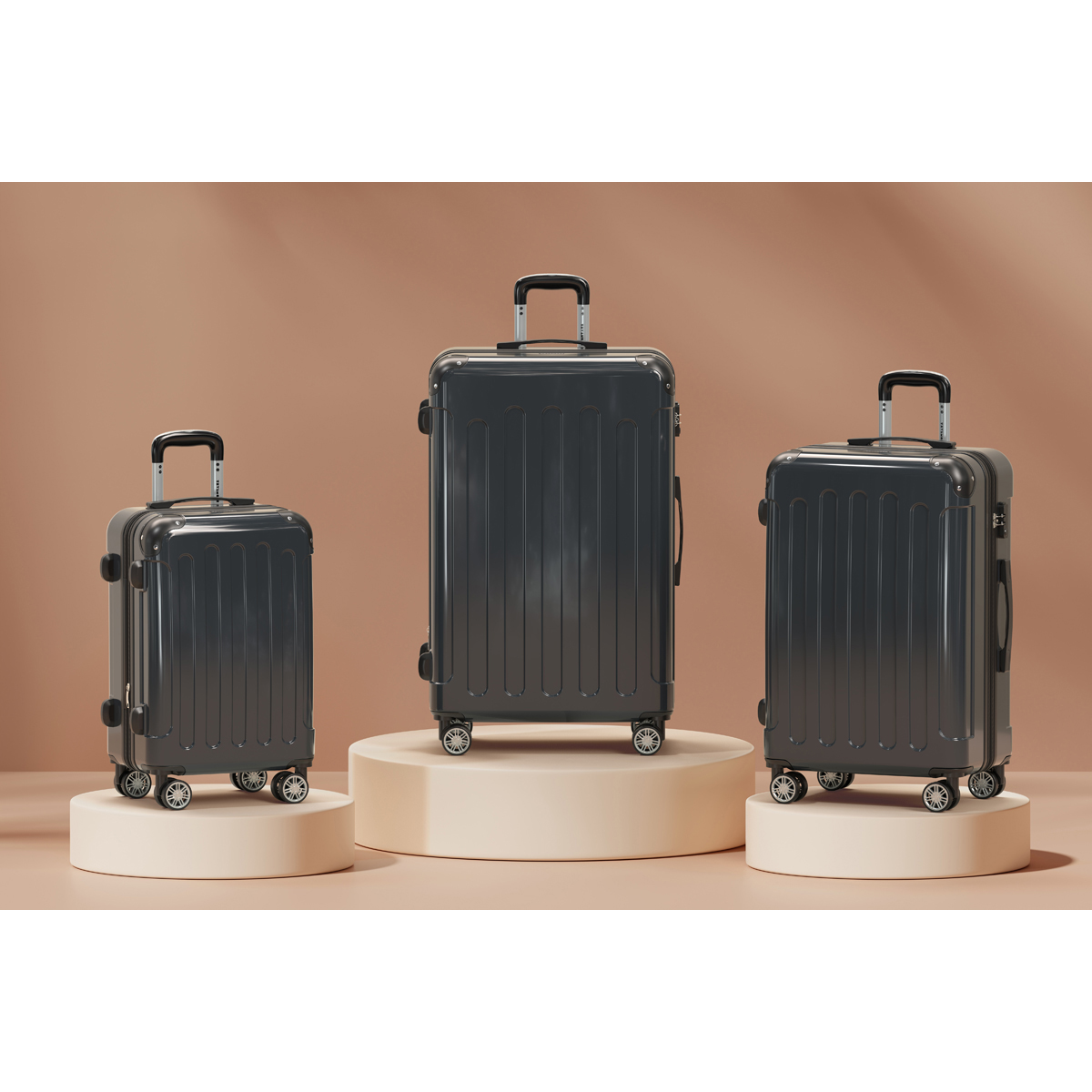 Three dark grey suitcases of varying sizes on display pedestals.