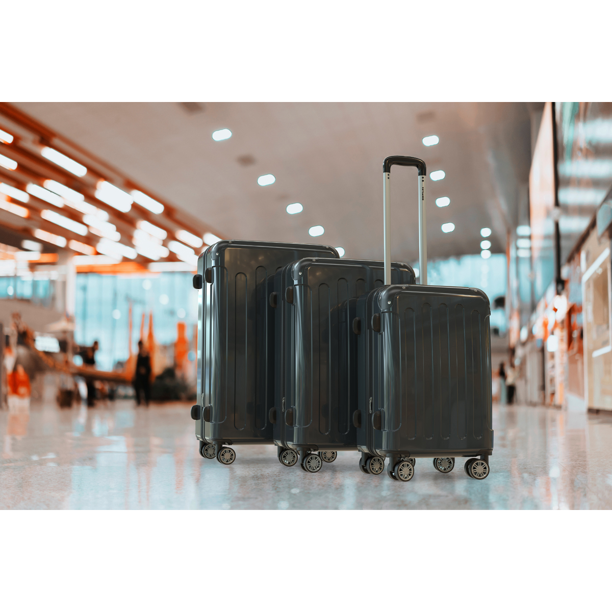 Three dark suitcases stand side-by-side in a bright, modern airport.