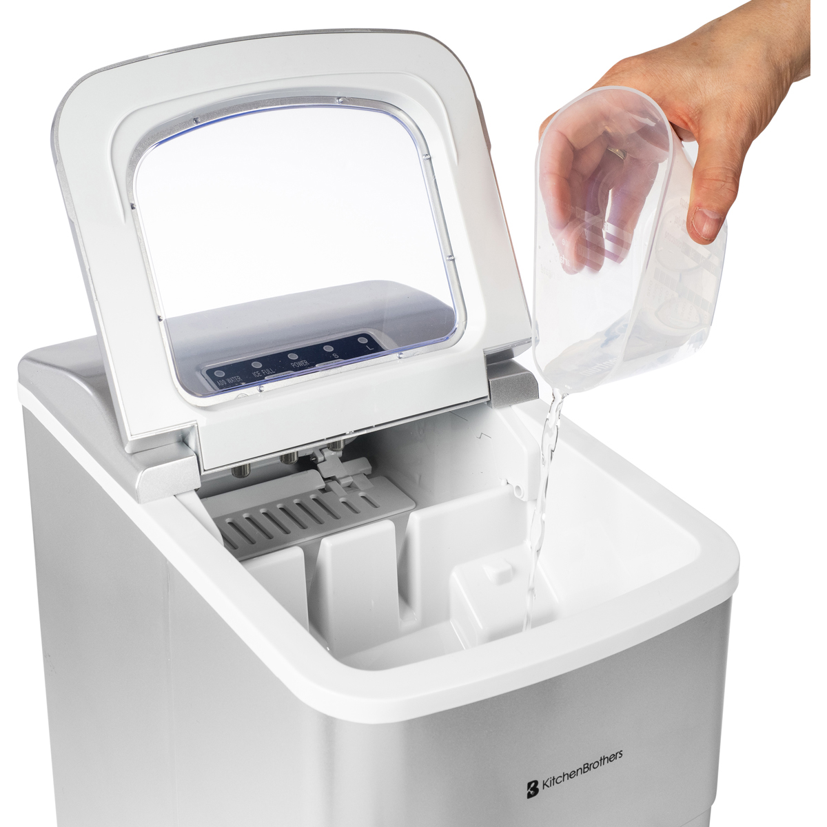 Ein Eiswürfelbereiter wird mit Wasser aus einem Messbecher befüllt.