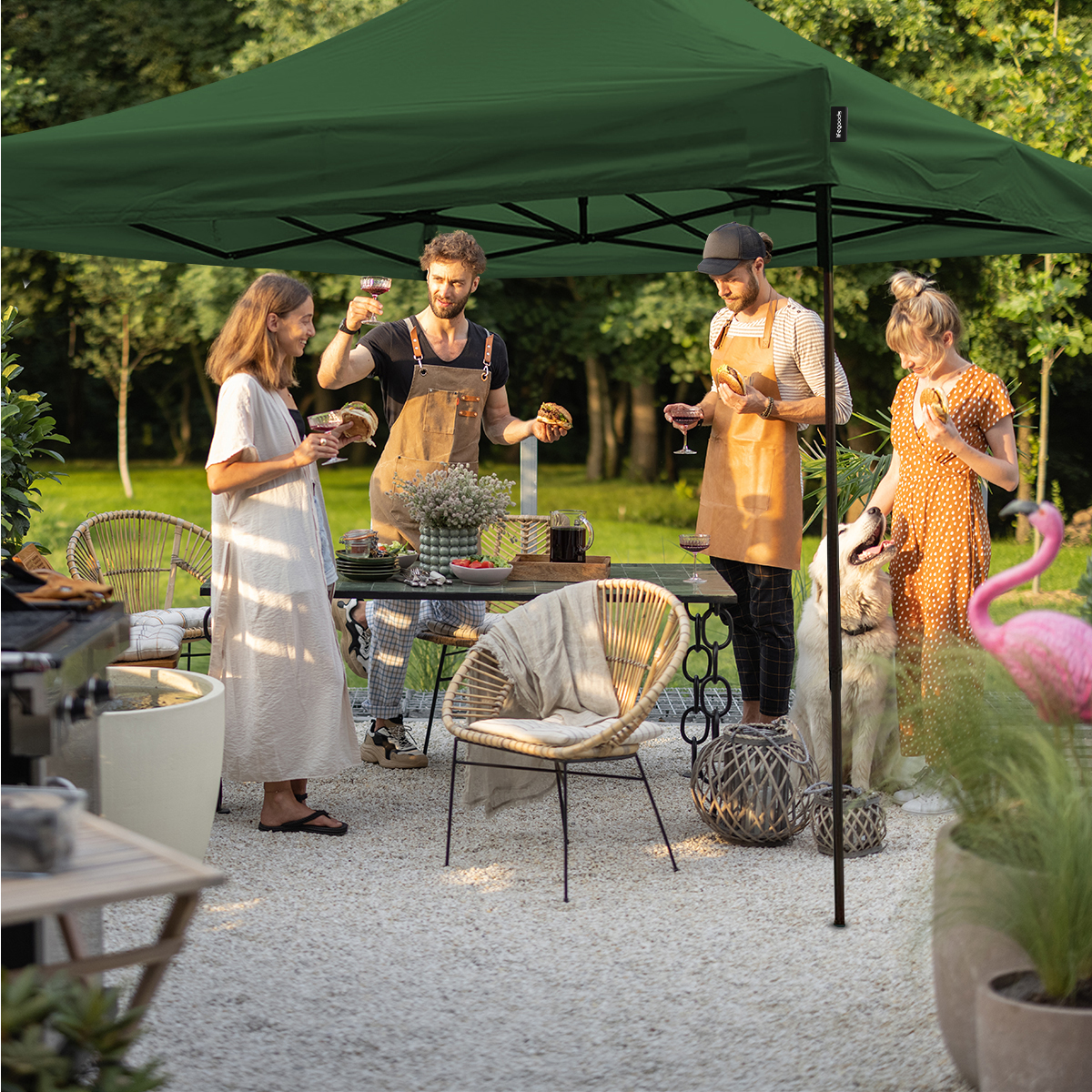 Four people and a dog enjoy an outdoor meal under a green canopy with burgers and wine.