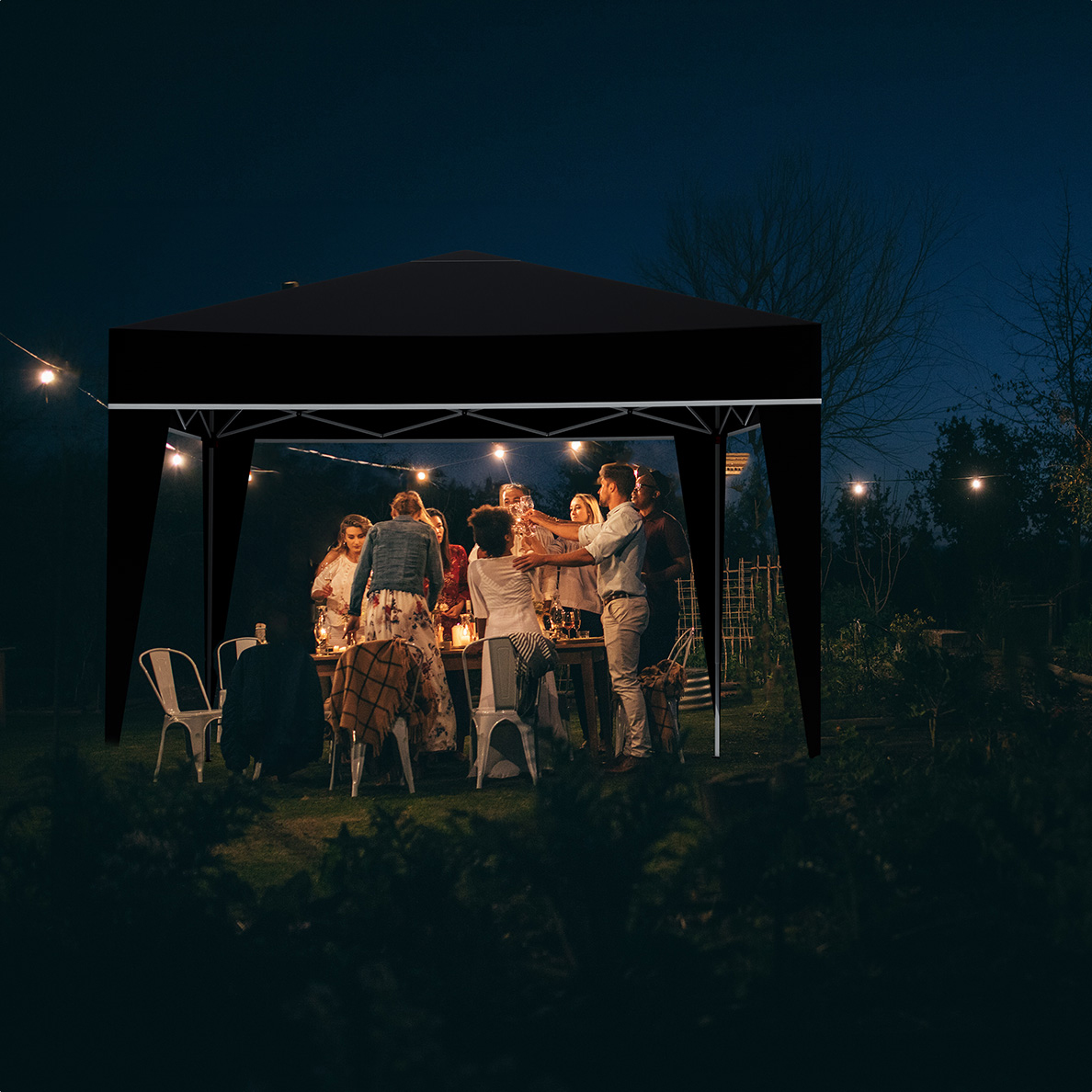 Des gens célèbrent sous un gazebo noir avec guirlandes, la nuit dans un jardin.