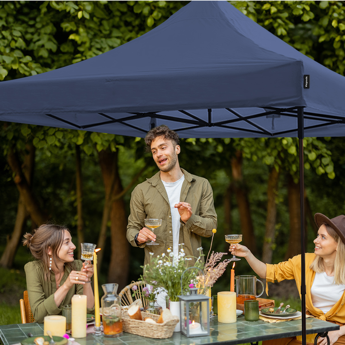 Three people under a blue canopy dining outdoors.