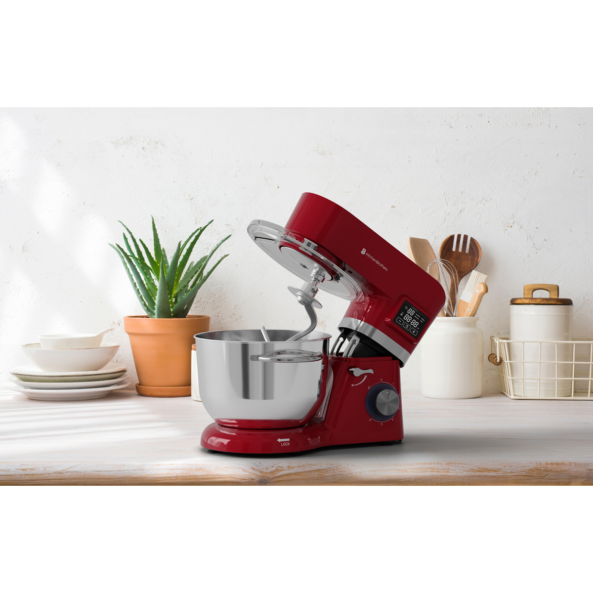 Een rode standmixer met roestvrijstalen kom en deeghaak op een houten aanrecht.