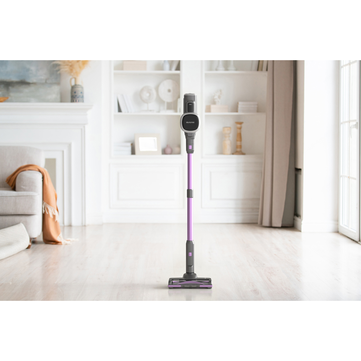 Un aspirateur sans fil violet se tient sur un parquet dans une pièce lumineuse.