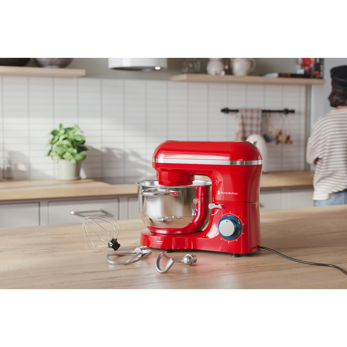 Un robot pâtissier rouge avec bol et accessoires est sur une table en bois.