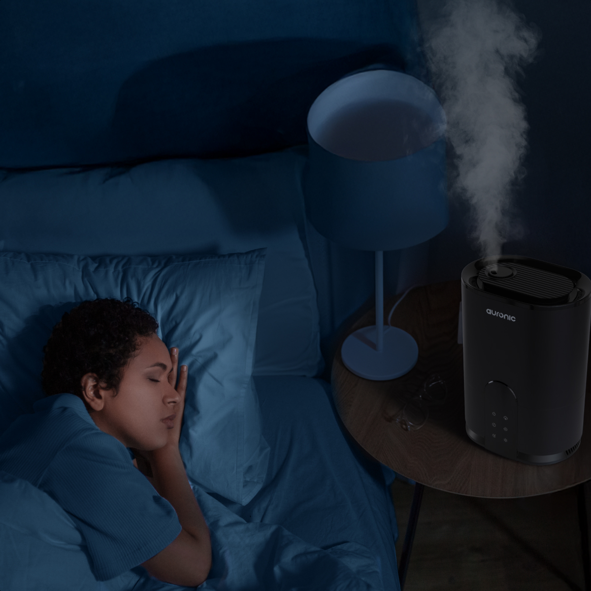 Eine Frau schläft im Bett, während ein Luftbefeuchter Nebel ausstößt.