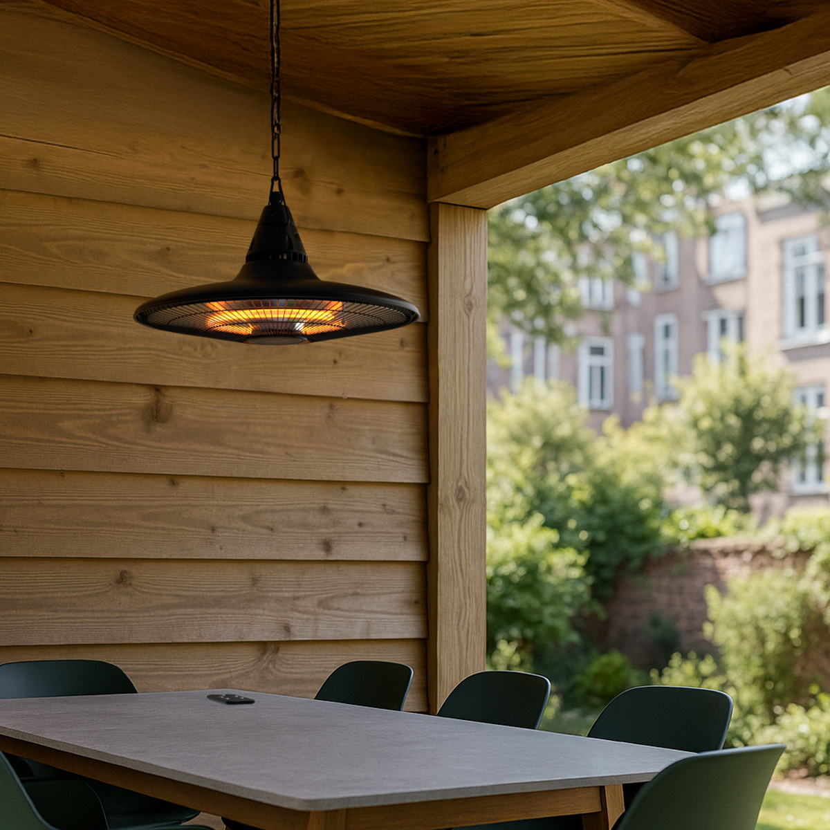 Un radiateur de terrasse suspendu au-dessus d'une table avec chaises, murs en bois et arbres derrière.